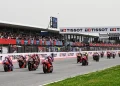 I motociclisti sfrecciano lungo la pista dell'Autódromo Internacional do Algarve, circondati dagli spettatori sugli spalti. Il circuito presenta il marchio Tissot su striscioni e strutture. I motociclisti indossano equipaggiamento colorato e la pista è fiancheggiata da erba.