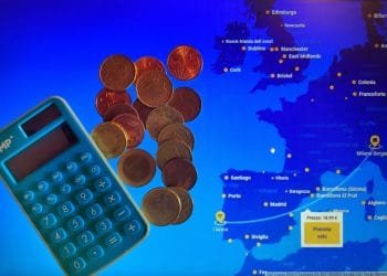 Una calcolatrice blu e diverse monete in euro sono posizionate su uno schermo che mostra una mappa dell'Europa con varie città contrassegnate. Un pulsante giallo sullo schermo mostra un prezzo del volo di 18,19 euro e il testo "Prenota Volo", che mostra irresistibili offerte voli Portogallo, che significa "Prenota Volo" in italiano.