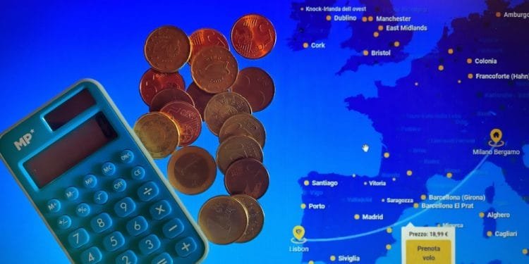 Una calcolatrice blu e diverse monete in euro sono posizionate su uno schermo che mostra una mappa dell'Europa con varie città contrassegnate. Un pulsante giallo sullo schermo mostra un prezzo del volo di 18,19 euro e il testo "Prenota Volo", che mostra irresistibili offerte voli Portogallo, che significa "Prenota Volo" in italiano.