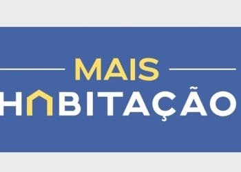 L'immagine presenta uno sfondo rettangolare blu con le parole "MAIS HABITAÇÃO" in testo giallo e bianco. La lettera "A" in "HABITAÇÃO" è stilizzata per assomigliare a una casa con il tetto giallo, a simboleggiare richieste di sostegno affitto per soluzioni abitative a prezzi accessibili.
