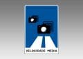 Un segnale stradale blu e bianco in Portogallo presenta due icone di telecamere che emettono onde di segnale, indicando autovelox. Dal basso si estendono due linee bianche che rappresentano una strada. Nella parte inferiore del cartello è riportata la dicitura "VELOCIDADE MÉDIA" (velocità media).