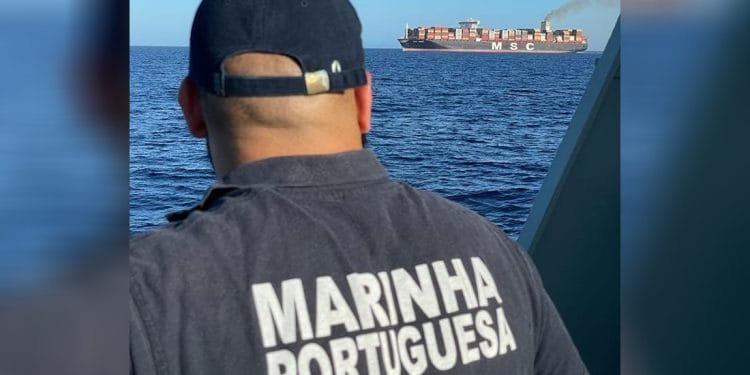 Una persona in uniforme della marina con la scritta "MARINHA PORTUGUESA" sulla schiena guarda il mare da una barca. La scena è cupa, forse legata ad una ragazza scomparsa in mare. In lontananza, sull'acqua è visibile una grande nave mercantile con la scritta "MSC" sulla fiancata, che emette una scia di fumo.