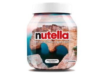 Un barattolo di Nutella con l'immagine di Praia da Marinha, una spiaggia pittoresca nella regione portoghese dell'Algarve con scogliere frastagliate e un arco naturale, sull'etichetta. Il testo sull'etichetta dice "Em casa temos o que é bom" e "Praia da Marinha", insieme al logo Ferrero.