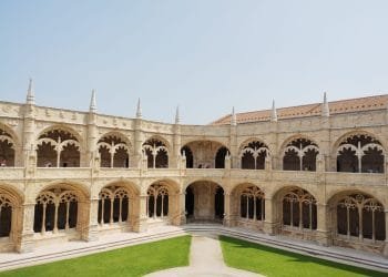 Un ampio cortile in pietra finemente scolpito con passaggi ad arco e guglie decorative, caratterizzato da un prato verde ben curato al centro. Il chiostro a due piani, spesso accessibile durante l'"ingresso gratuito musei portoghesi", vanta un design architettonico caratteristico degli stili gotico e manuelino.