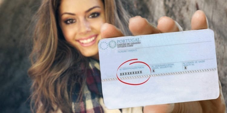 Una donna con i capelli lunghi e una sciarpa scozzese tiene in mano una tessera del cittadino portoghese verso la telecamera. La scheda mostra la sua foto e le informazioni personali, sebbene il numero di identificazione sia oscurato da una X per motivi di privacy. Se devi ottenere NIF Portogallo, avere questa carta è essenziale. Lo sfondo è sfocato.