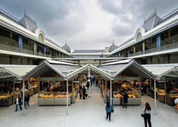 Vivace mercato coperto dal design ampio e moderno, caratterizzato da varie bancarelle che vendono merci sotto una tettoia di vetro. La gente fa la spesa e passeggia. Ricorda il mercado Bolhão Porto, il mercato è ospitato in un grande edificio dall'aspetto storico con dettagli architettonici decorati.
