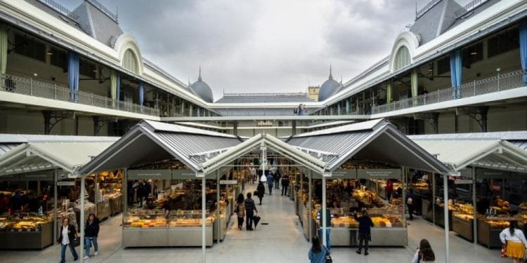 Vivace mercato coperto dal design ampio e moderno, caratterizzato da varie bancarelle che vendono merci sotto una tettoia di vetro. La gente fa la spesa e passeggia. Ricorda il mercado Bolhão Porto, il mercato è ospitato in un grande edificio dall'aspetto storico con dettagli architettonici decorati.