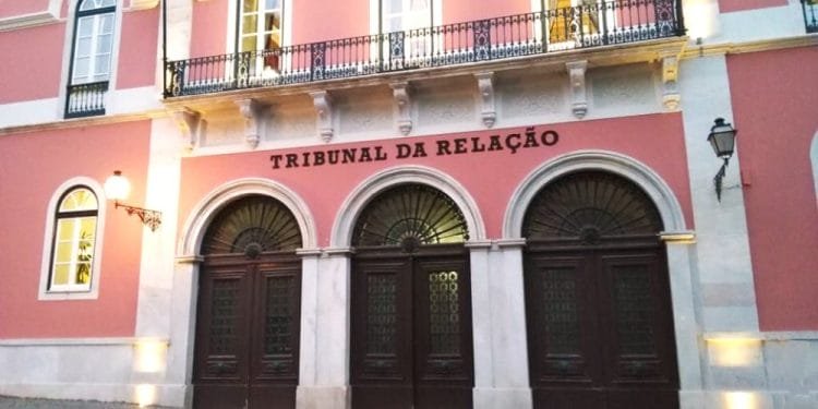 Un grande edificio color rosa con ingressi ad arco, ciascuno con grandi porte in legno scuro e dettagli in ferro battuto. Sopra le porte, l'insegna recita "Tribunal da Relação". Sulla sinistra è visibile una bandiera portoghese, attaccata al livello superiore dell'edificio: uno spettacolo imponente per ogni genitore minore tolto.
