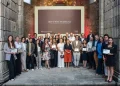 Un gruppo di persone, vestite con abiti business casual, sta in posa per la premiazione Best Of Wine Tourism in Porto 2026, tenendo in mano i diplomi. La foto è scattata al chiuso tra due imponenti muri e difronte ad un maxischermo.