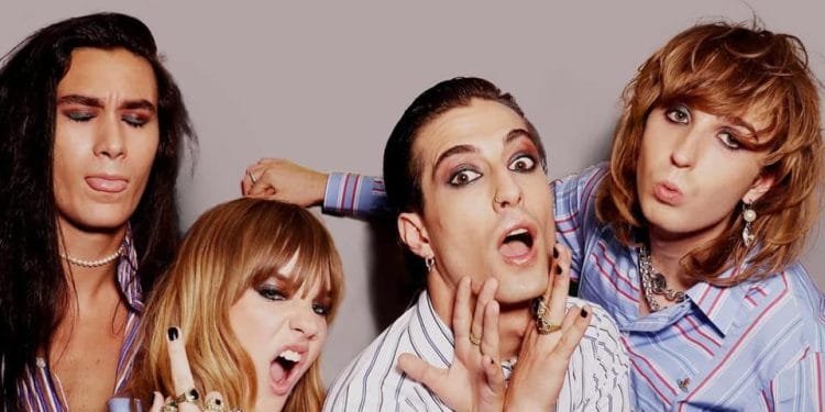 Quattro persone con volti espressivi posano in modo giocoso su uno sfondo semplice. Hanno un trucco occhi drammatico e indossano abiti eleganti e coordinati con strisce. Una persona tira fuori la lingua, un'altra ha la bocca aperta e le altre ancora imbronciate con espressioni esagerate, incanalando l'energia della prima esibizione dei Maneskin in Portogallo.