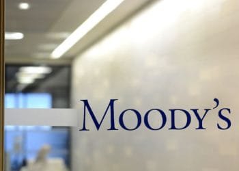 Una porta a vetri con la parola "Moody's" scritta in caratteri blu. Dietro il vetro, c'è un corridoio di un ufficio con un'illuminazione intensa e una vista sfocata di uno spazio ufficio, probabilmente dove si svolgono le discussioni sulla valutazione del Portogallo.