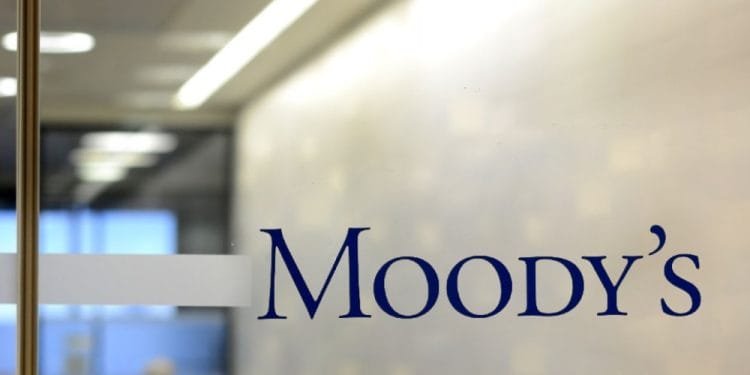 Una porta a vetri con la parola "Moody's" scritta in caratteri blu. Dietro il vetro, c'è un corridoio di un ufficio con un'illuminazione intensa e una vista sfocata di uno spazio ufficio, probabilmente dove si svolgono le discussioni sulla valutazione del Portogallo.