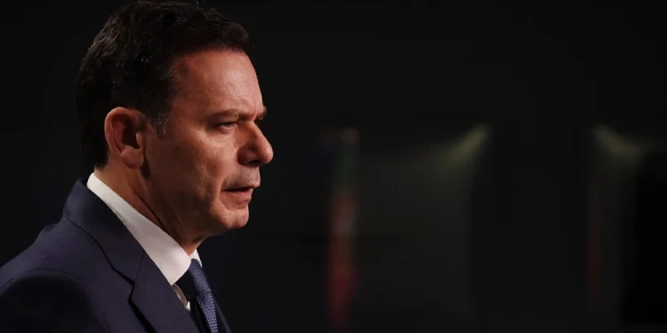 Luis Montenegro, in giacca e cravatta parla al microfono della crisi di governo in Portogallo, su uno sfondo scuro; la luce mette in risalto la sua espressione seria mentre affronta l'argomento delle elezioni anticipate.