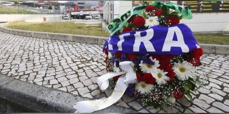 Una ghirlanda floreale a memoria di Marco Ficini l'uomo travolto a Lisbona. Con fiori rossi, bianchi e verdi è posizionata su una superficie di ciottoli, parzialmente coperta da una sciarpa blu e bianca con la scritta "ULTRA". Alla ghirlanda è attaccato anche un nastro.