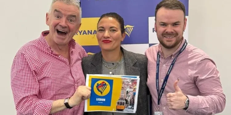 Annunciando nuovi voli Ryanair verso il Portogallo, Michael O'Leary solleva con entusiasmo un cartello blu con la scritta "ROMA 2024", "7 NUOVE ROTTE" e "RYANAIR".