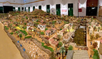 Un diorama in miniatura dettagliato di Vila Real Santo Antonio presenta piccoli edifici, alberi e statuette su un grande tavolo. La scena vivace include sentieri e un piccolo specchio d'acqua, catturando lo spirito vivace di questa vivace comunità.