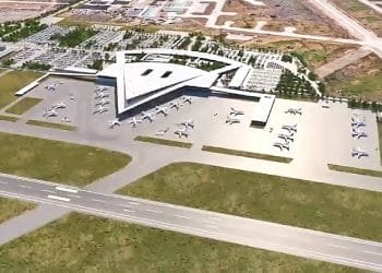 Veduta aerea del nuovo aeroporto di Lisbona con il caratteristico terminal a forma di stella. Intorno al terminal sono parcheggiati numerosi aerei. Le aree circostanti includono parcheggi, strade di accesso e terreni non edificati. Una pista si incrocia davanti al terminal.