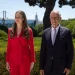 La Principessa Leonor di Spagna e il Presidente della repubblica portoghese Marcelo rebelo de Sousa stanno fianco a fianco all'aperto durante la visita ufficiale a Lisbona. Stanno entrambi sorridendo. Sullo sfondo si trovano siepi verdi rigogliose e un albero, insieme a un grande ponte e altre strutture contro un cielo limpido.