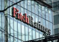 Un edificio con facciata in vetro riflettente mostra il logo Fitch Ratings in evidenza a grandi lettere in Portogallo. La parola Fitch è in rosso e Ratings è in nero.