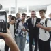 Un gruppo di tre giovani con Luis Montenegro, tutti sorridenti e che alzano il pollice, immagine inserita nel contesto della Legge di bilancio del Portogallo ( Orçamento de Estado ). La scena è stata catturata su uno smartphone da qualcuno in primo piano, in mezzo a un ambiente interno luminoso e moderno.