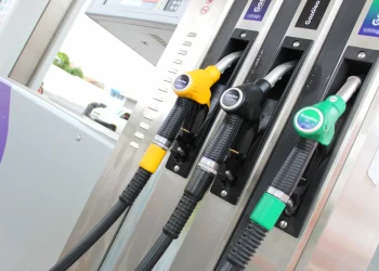 Una fila di ugelli di pompe di carburante in una stazione di servizio con differenti prezzi e colori tra benzina e diesel di una stazione di servizio in Portogallo. Le maniglie gialle e verdi per diversi tipi di benzina, mentre la nera per il diesel.