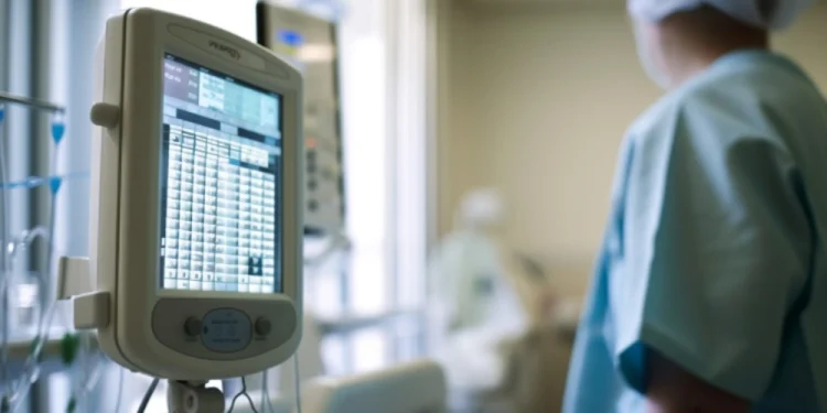 Un professionista medico in camice è in piedi in una stanza d'ospedale a supporto del trattamento di cura del cancro in Portogallo, osservando attentamente un paziente. Una vista ravvicinata di un monitor medico mostra i segni vitali.