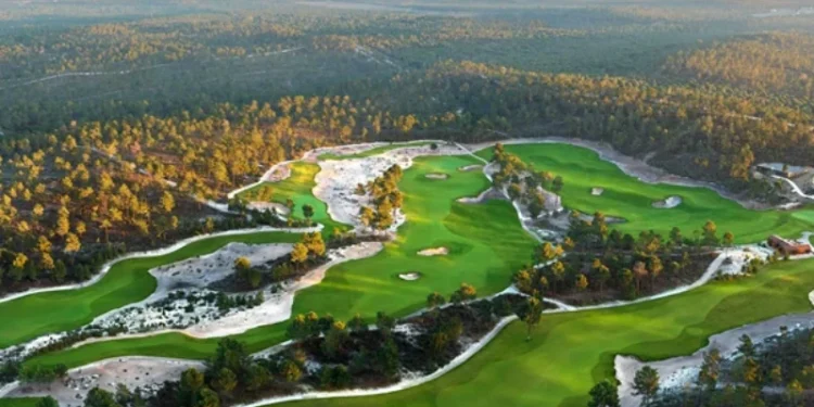 Vista aerea dei campi da golf di Terras da Comporta in Portogallo, un' Eccellenza in Destinazione Golfistica, con fairway verdeggianti e trappole di sabbia, circondato da una fitta foresta sotto un cielo terso. Il paesaggio si estende in lontananza, mostrando verdi vibranti e toni terrosi.