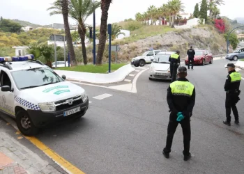 Gli agenti della polizia stanno cominando una multa del traffico su una strada in Spagna, che sarà poi da pagare. Con l'auto della polizia parcheggiata di lato, gli agenti con i giubbotti ad alta visibilità parlano con gli automobilisti.