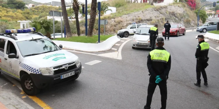 Gli agenti della polizia stanno cominando una multa del traffico su una strada in Spagna, che sarà poi da pagare. Con l'auto della polizia parcheggiata di lato, gli agenti con i giubbotti ad alta visibilità parlano con gli automobilisti.