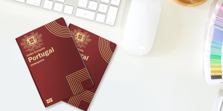 Due esemplari del Nuovo Passaporto elettronico portoghese sono su una scrivania bianca de designer accanto a una tastiera, un mouse per computer, una tazza di caffè fumante e campioni di colori vivaci. La scena cattura l'essenza del flusso creativo, forse come parte di un design da concorso stimolante.