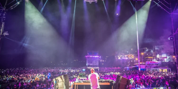 Concerto notturno all'aperto di capodanno, un DJ elettrizza la folla di Albufeira con luci e attrezzature vibranti, infondendo energia all'aria dell'Algarve. Mentre i festeggiamenti del capodanno si accendono intorno a loro, il pubblico si crogiola nell'atmosfera vivace circondata da luci abbaglianti del palco.