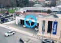 Vista aerea della stazione di polizia a Porto con diverse auto della polizia parcheggiate all'esterno in servizio contro il parcheggio irregolare. L'edificio mostra un grande cartello "Polícia" e presenta pannelli solari sul tetto. Circondata da edifici residenziali sullo sfondo.