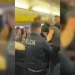 Agenti di polizia all'interno del corridoio di un aereo Ryanair, intenti a gestire una situazione che coinvolge un passeggero molesto. Alcuni passeggeri sono seduti e osservano l'evento.
