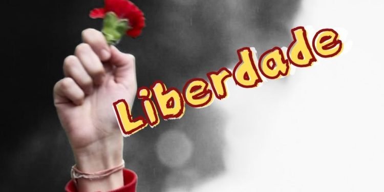 Manifesto per elogiare la parola portoghese dell'anno. Una mano alzata tiene un garofano rosso su uno sfondo bianco e nero. La parola "Liberdade", appare in giallo con un contorno rosso accanto, catturando lo spirito del momento iconico che rappresenta.