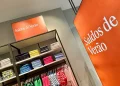 L'interno del negozio di abbigliamento è caratterizzato da due vivaci cartelli arancioni con la scritta "Saldos de Verão" che annunciano i saldi estivi, ovvero i vivaci saldi in Portogallo.Si vedono camicie colorate piegate, ordinatamente impilate sugli scaffali.
