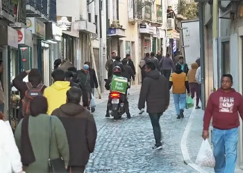 A Martim Moniz di Lisbona in Portogallo, dove vivono molti immigrati, si sta generando xenofobia. I questa strada stretta acciitolata alcuni indossano giacche e portano borse della spesa. Un fattorino di cibo a domicilio su uno scooter si prepara a farsi strada tra la gente.