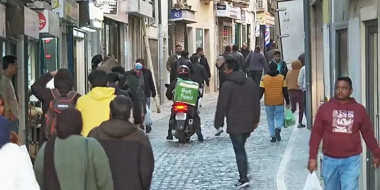 A Martim Moniz di Lisbona in Portogallo, dove vivono molti immigrati, si sta generando xenofobia. I questa strada stretta acciitolata alcuni indossano giacche e portano borse della spesa. Un fattorino di cibo a domicilio su uno scooter si prepara a farsi strada tra la gente.