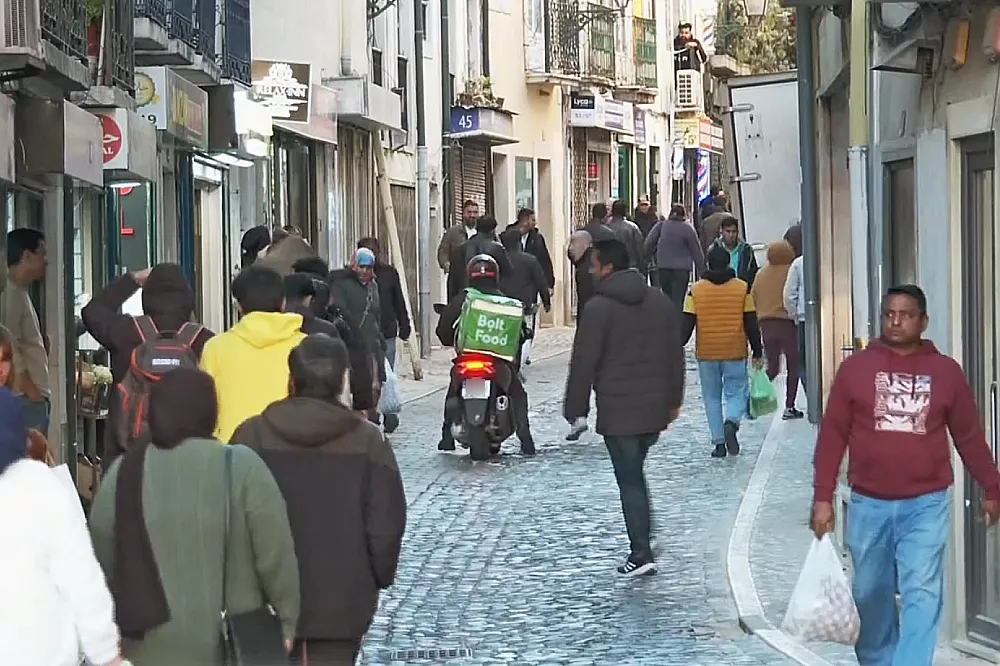 A Martim Moniz di Lisbona in Portogallo, dove vivono molti immigrati, si sta generando xenofobia. I questa strada stretta acciitolata alcuni indossano giacche e portano borse della spesa. Un fattorino di cibo a domicilio su uno scooter si prepara a farsi strada tra la gente.