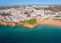 Adagiata lungo una spiaggia sabbiosa, di Albufeira città con i suoi edifici bianchi densamente ammassati su una collina si affaccia sull'oceano turchese. Circondata da verdi colline e un cielo azzurro e limpido, Albufeira vanta scogliere mozzafiato lungo la sua costa.