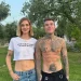 Chiara Ferragni con un crop top bianco e jeans è in piedi accanto a Fedez senza maglietta con tatuaggi in un'area erbosa con alberi, non in Portogallo, bensì sono in Puglia. Sorridono sotto le luci scintillanti, catturando l'essenza di un'atmosfera.