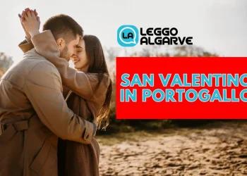 Una coppia in cappotto si abbraccia all'aperto, circondata da terreno sabbioso e alberi celebrando San Valentino in Portogallo, come scritto nella grafica.