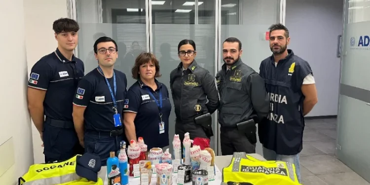Un gruppo di sei doganieri, in uniforme, sta dietro un tavolo su cui sono esposti vari oggetti confiscati. Gilet ad alta visibilità con la scritta "Dogane" e "Guardia di Finanza" sono drappeggiati sul tavolo in seguito al recente sequestro di cocaina tra Lisbona e Firenze che ha portato a un arrestato.