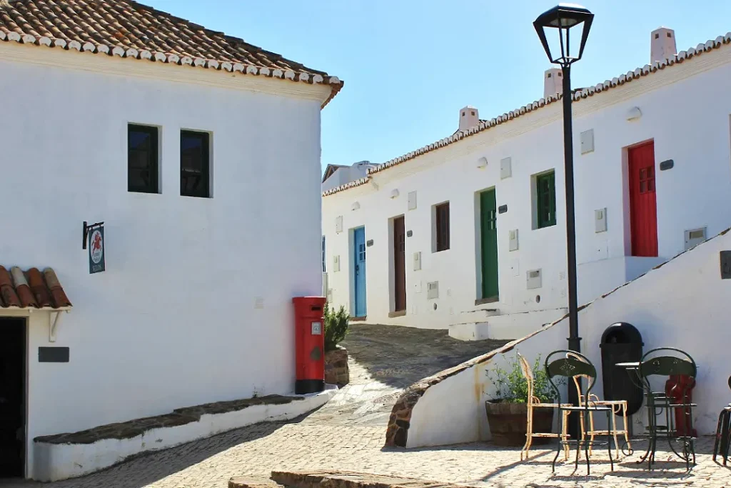 Uno scorcio da visitare del villaggio di Pedralva in Algarve dove si vedono le tipiche case bianche delle porte colorate di rosso verde e blu. 
