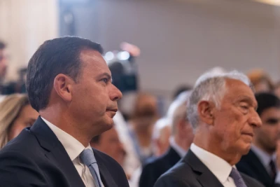 Luís Montenegro e Marcelo Rebelo de Sousa, in giacca e cravatta, sono ora i protagonisti della crisi di governo in Portogallo. Sono seduti in mezzo ad una platea con espressioni pensierose.