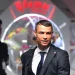 Cristiano Ronaldo in abiti eleganti all'ingresso di un cinema. Si vede sfuocato sullo sfondo un altro uomo con un cappellino e un'insegna luminosa.
