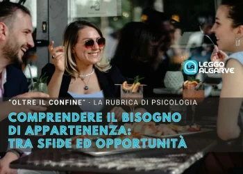 Tre persone siedono al tavolo di un bar all'aperto, sorridendo e chiacchierando mentre bevono qualcosa, soddisfando il bisogno di appartenenza ad un gruppo. Un testo in italiano si sovrappone all'immagine, spiegando che si tratta di una cover di una rubrica di psicologia.