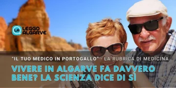 Una coppia di anziani che sembrano vivere bene, indossa occhiali da sole e sorride si trova su una soleggiata spiaggia dell' Algarve in Portogallo con scogliere sullo sfondo. Il testo parla dei benefici di vivere bene in Algarve, citando la scienza.