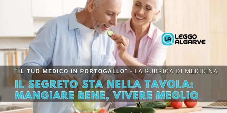 Un uomo e una donna anziani sorridono mentre preparano bene del mangiare sano in una cucina luminosa, dove si può vivere meglio. L'uomo assaggia una fetta di cetriolo. Il testo sovrapposto in italiano, "Mangiare bene, vivere meglio".