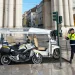 Un tuk-tuks parcheggiato a Lisbona e un poliziotto che si accinge ad emettere la multa. Si vede anche una moto e dei palazzi antichi sullo sfondo.