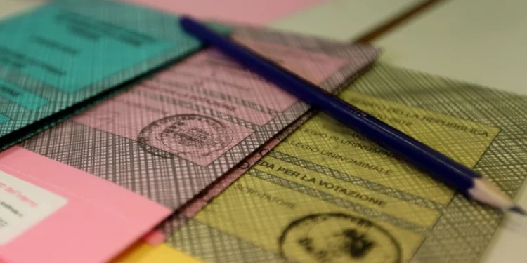 Diverse schede del Referendum 2025 colorate – verde, rosa e giallo – sono disposte su un tavolo probabilmente per italiani residenti all estero. Si vede una matita blu sopra, le schede includono timbri ufficiali e un testo visibile in italiano per i residenti all'estero.